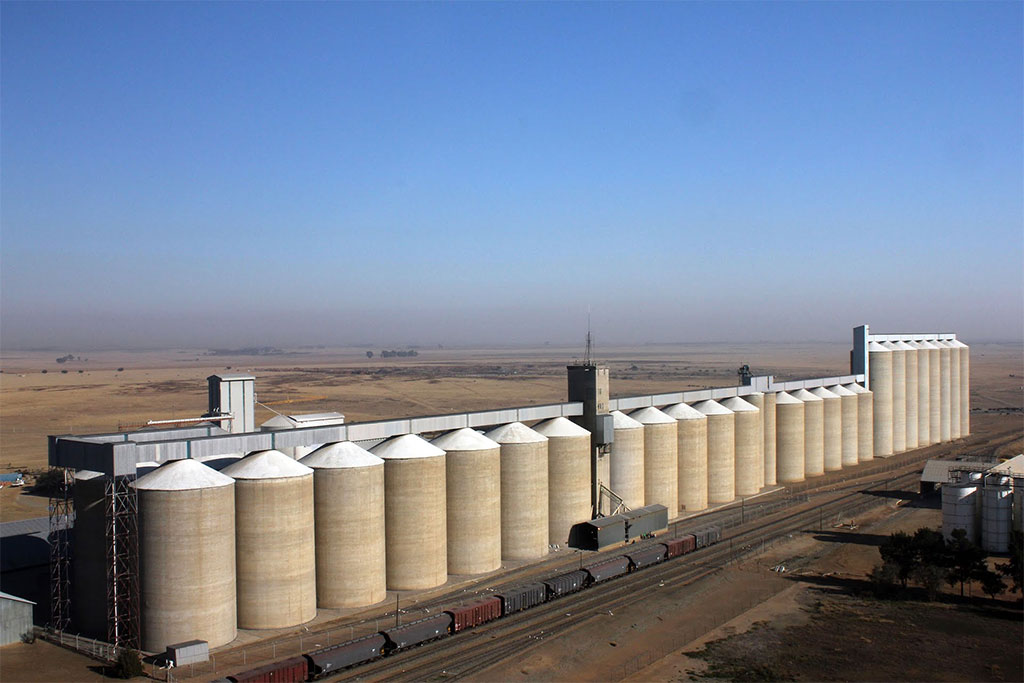 Large grain storage silos at Senwes in Wesselsbron, Free State, South Africa, with railway wagons alongside the facility, illustrating the country's maize reserves amid the global crossfire of rising agricultural costs, El Niño and grain-price uncertainty in 2027.